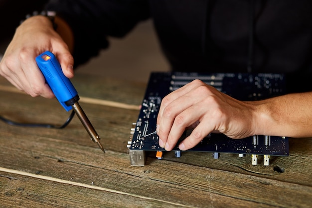 Engenheiro ou técnico repara placa de circuito eletrônico com ferro de soldar.