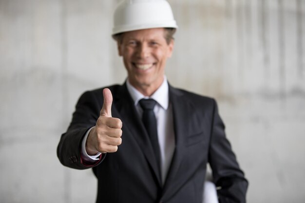 Engenheiro profissional sorridente no capacete mostrando o polegar para cima