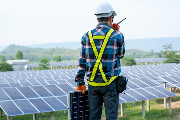 Engenheiro trabalhando na verificação e manutenção de equipamentos elétricos em estações de usinas de energia solar, energia renovável e conceitos de energia solar.