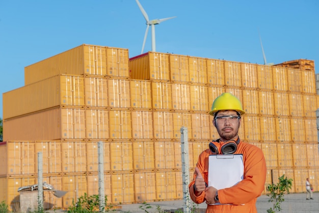 Engenheiro trabalhando no local para manter o contêinerForeman usando capacete em pé no pátio de contêineres e verificar a integridade do contêiner