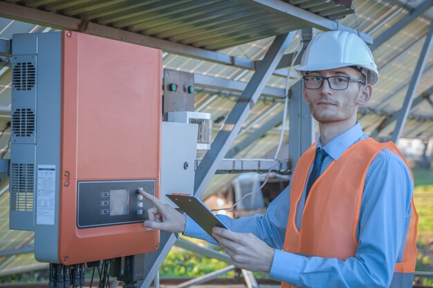 Engenheiro, um homem de uniforme verifica o sistema de controle da estação solar