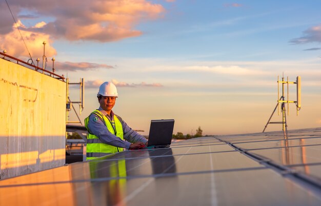 Engenheiro usando laptop em painéis solares no telhado no céu do sol, um engenheiro que trabalha em uma fazenda fotovoltaica. eco tecnologia para energia elétrica