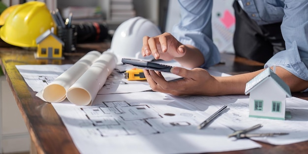 Engenheiro verifica plantas de construção em novo projeto com ferramentas de engenharia na mesa do escritório