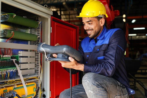 Engenheiro verificando o painel de controle e ensinando novo braço robótico automático e máquina de controle operacional na fábrica