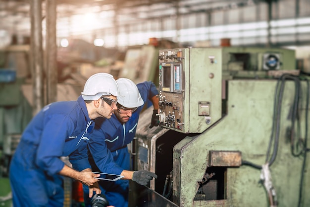 Engenheiro verificando o serviço de manutenção da máquina com uma equipe trabalhando em equipe em uma fábrica pesada de aço