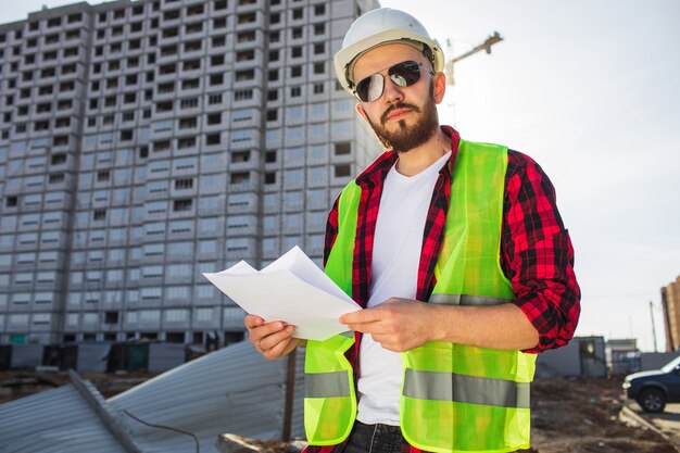 Engenheiro verificando plantas do canteiro de obras