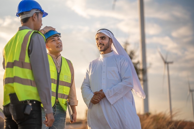 Engenheiros asiáticos e empresário árabe verificando e inspecionando a construção com céu pôr do sol