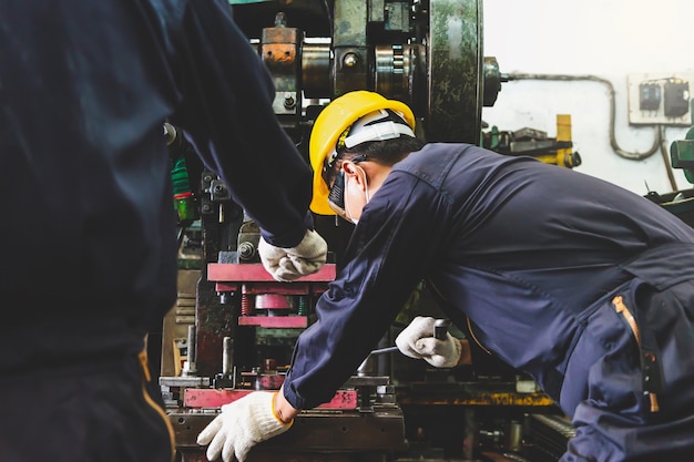 Foto engenheiros da fábrica de metal com capacete, máscara facial e luvas estão segurando os tablets para trabalhar na manufatura técnica de peças de metal com tornos dentro de uma instalação industrial.