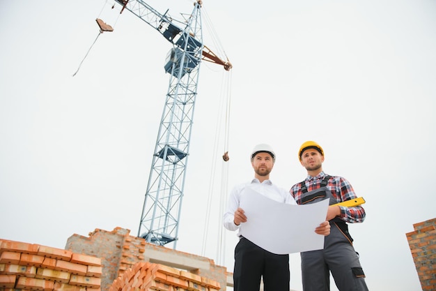 Engenheiros de construção que supervisionam o progresso do projeto de construção ficam no novo telhado de piso de concreto e fundo de guindaste