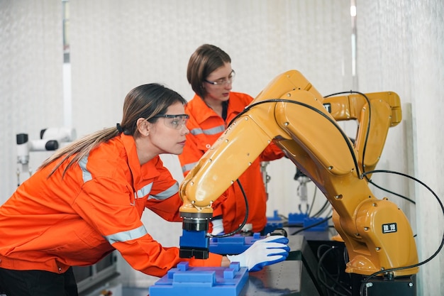Engenheiros de controle de robótica resolvem problemas e configuram a programação do painel de controle para o controlador de braço de robô industrial na planta de produção