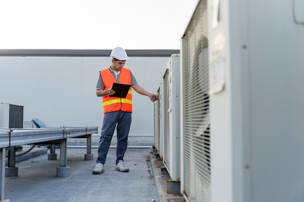 Engenheiros de fábrica caminhando e verificando o sistema de refrigeração da fábrica O capataz registra a condição do compressor antes da manutenção de acordo com o plano de manutenção