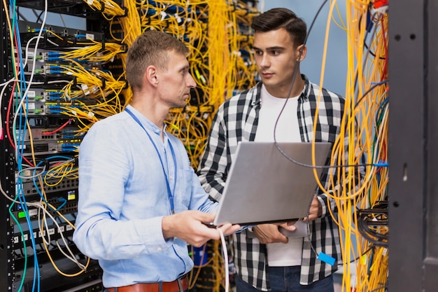 Foto engenheiros de rede trabalhando em uma sala de servidores com um laptop