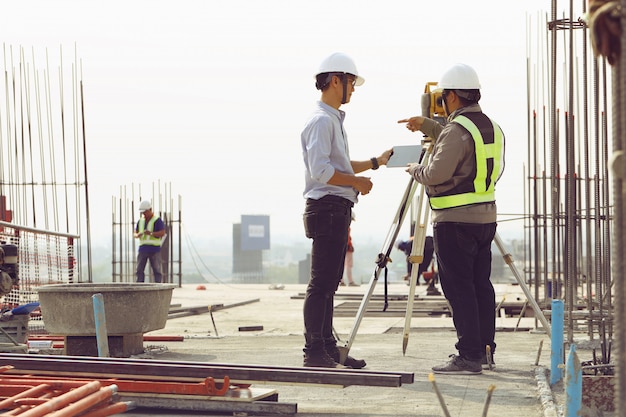 Foto engenheiros e funcionários estão inspecionando os edifícios usando o teodolito.