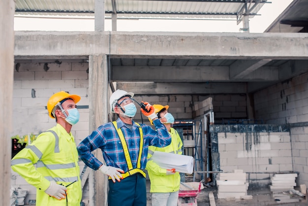 Engenheiros e trabalhadores da construção civil usando máscaras no trabalho
