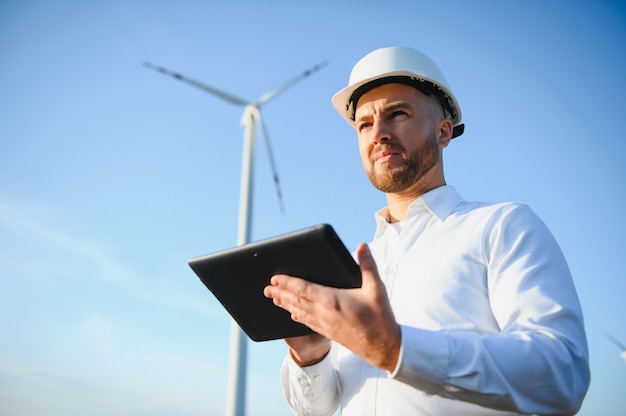 Engenheiros elétricos trabalhando em uma estação geradora de energia de turbina eólica com um laptop