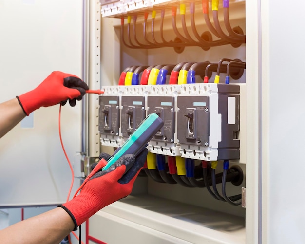 Engenheiros elétricos verificam dispositivos de controle elétrico com um multímetro