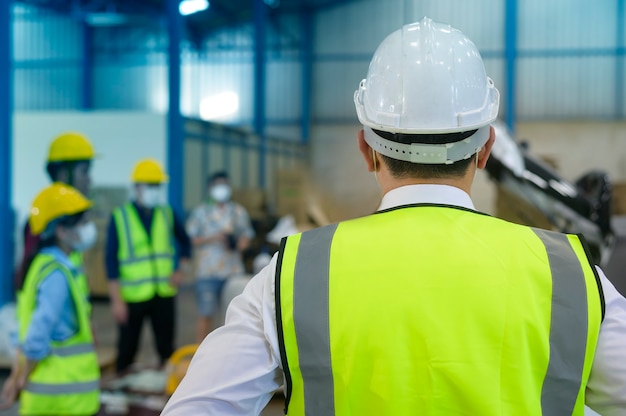 Engenheiros estão colocando um capacete de proteção na cabeça no armazém