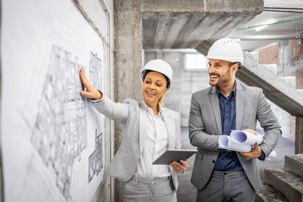 Engenheiros estruturais com plano de projeto e computador controlando e inspecionando o processo de construção