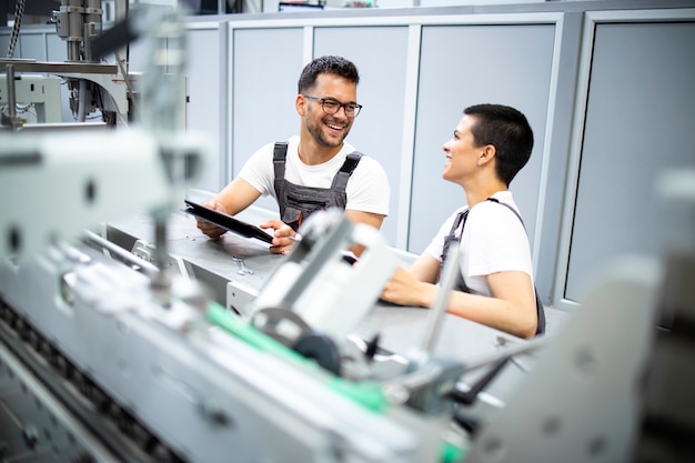Engenheiros experientes prestando serviços de manutenção a máquinas de fabricação industrial modernas na fábrica de produção.