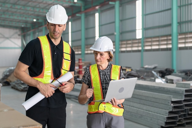 Engenheiros industriais, homens e mulheres, usam laptop e projetos de desenho, verificam produtos