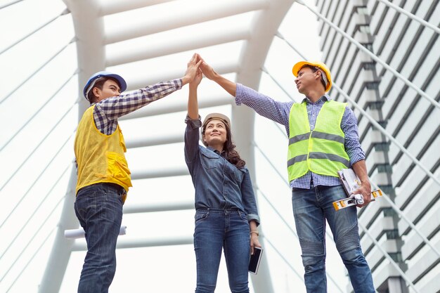 Engenheiros levantaram a mão para o céu juntos. conceito de negócio de trabalho em equipe e sucesso.