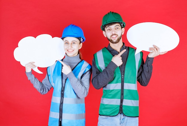 Engenheiros masculinos e femininos com capacete segurando uma placa de informações de forma oval e nuvem.