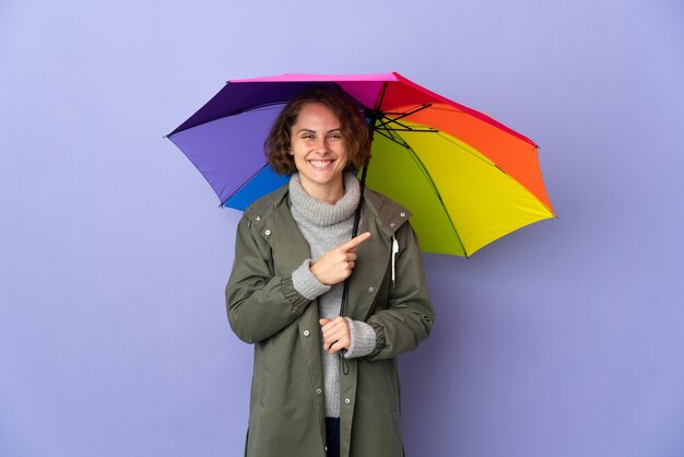 Englische Frau, die einen isolierten Regenschirm hält, der zur Seite zeigt, um ein Produkt zu präsentieren