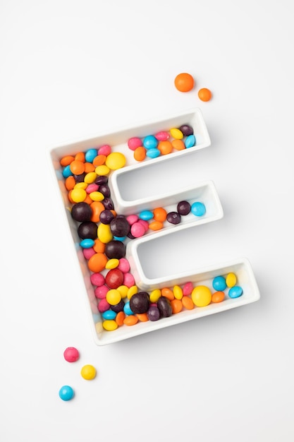 Englischer Buchstabe E aus bunten Bonbons auf weißem Hintergrund