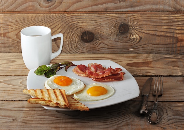 Englisches Frühstück mit Rührei, Speck, gebratenem Toast und Tee