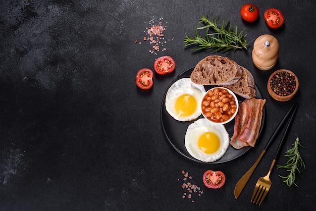 Englisches Frühstück mit Spiegeleiern, Speckbohnen, Tomaten, Gewürzen und Kräutern