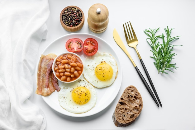 Englisches Frühstück mit Spiegeleiern, Speckbohnen, Tomaten, Gewürzen und Kräutern