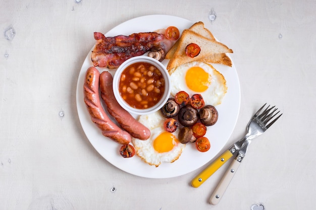 Englisches Frühstück mit Spiegeleiern, Tomaten, Würstchen, Speck, Pilzen, Toast und Bohnen