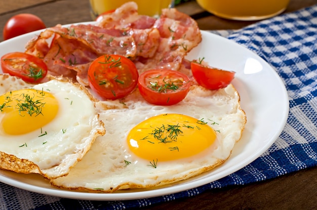 Englisches Frühstück mit Toast, Ei, Speck und Gemüse in einer rustikalen Art auf Holztisch