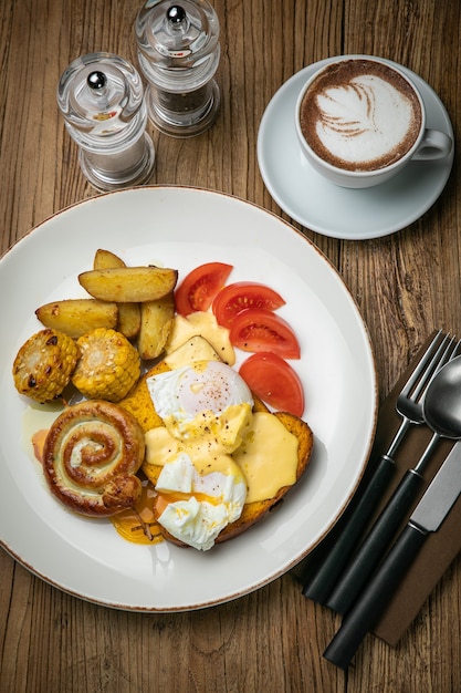 Englisches Frühstück mit Toast, pochiertem Ei, Sauce und Wurst auf einem Holztisch