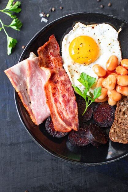 englisches Frühstück Spiegelei Blutwurst Blutwurst Müsli Brot Bohnen Rührei auf dem Tisch