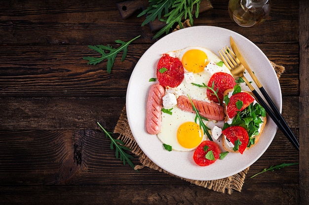 Englisches Frühstück - Spiegeleier, Würstchen, Tomaten und Feta-Käse. Amerikanisches Essen. Draufsicht, Overhead, Speicherplatz