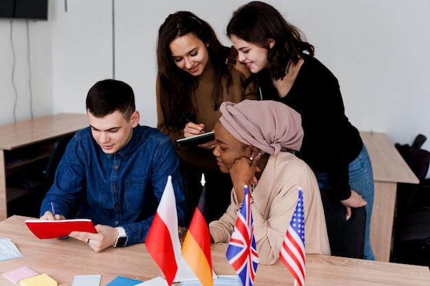 Englischunterricht mit Studenten aus verschiedenen Ländern: Polen, Deutschland, USA. Zusammenarbeit. Arbeiten in multiethnischen Studenten. Lehrer lernen gemeinsam Fremdsprachen im Unterricht. Studieren mit Laptop.