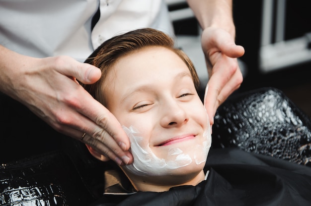 Engraçadinho em uma capa de salão preto na barbearia