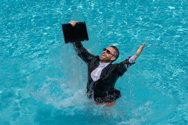 Engraçado empresário animado de terno com laptop na piscina homem de negócios louco nas férias de verão