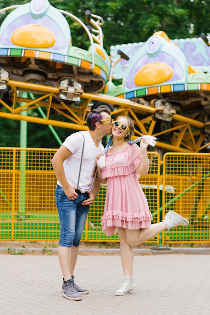 Engraçado engraçado e engraçado casal apaixonado, um garoto e uma garota de óculos de sol estão sorrindo e felizes em um parque de diversões