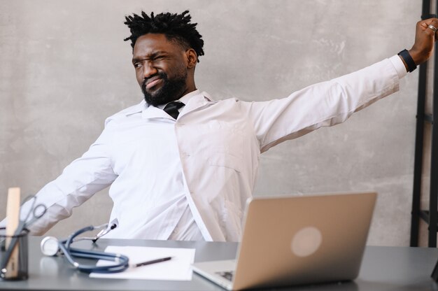 Foto engraçado entediado no trabalho trabalhador médico afro-americano adormecendo na mesa do escritório