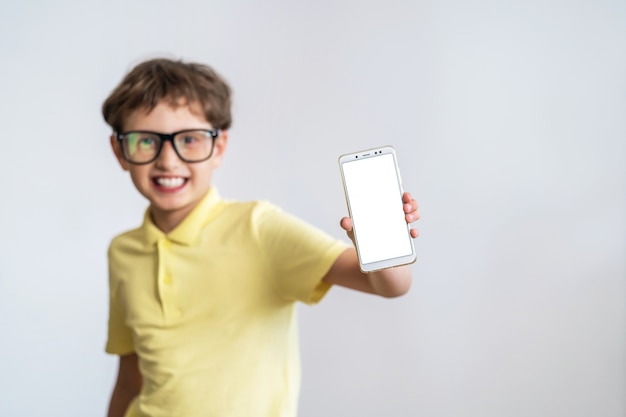 Engraçado estudante inteligente com óculos mostra a tela branca do seu celular.