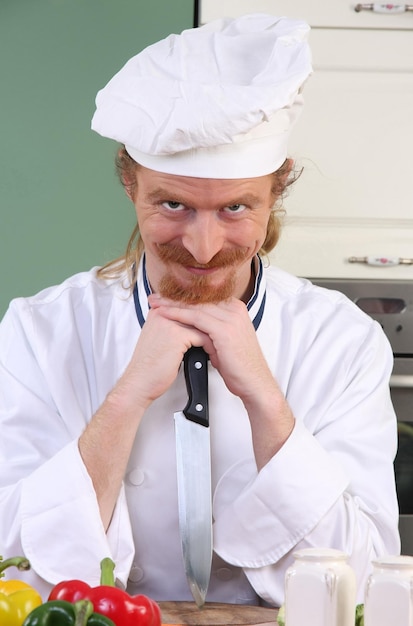 Engraçado jovem chef com uma faca na cozinha