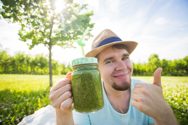 Engraçado jovem contém smoothie de desintoxicação com canudo. Conceito de estilo de vida saudável, pessoas e alimentos.