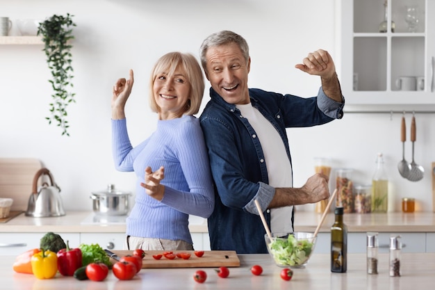 Foto engraçado marido e mulher sênior se divertindo enquanto cozinha