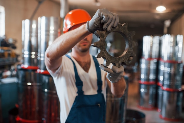 Engranaje mecánico. El hombre de uniforme trabaja en la producción. Tecnología industrial moderna.