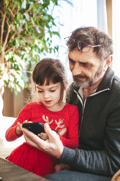 Enkelin und Großvater mit Smartphone