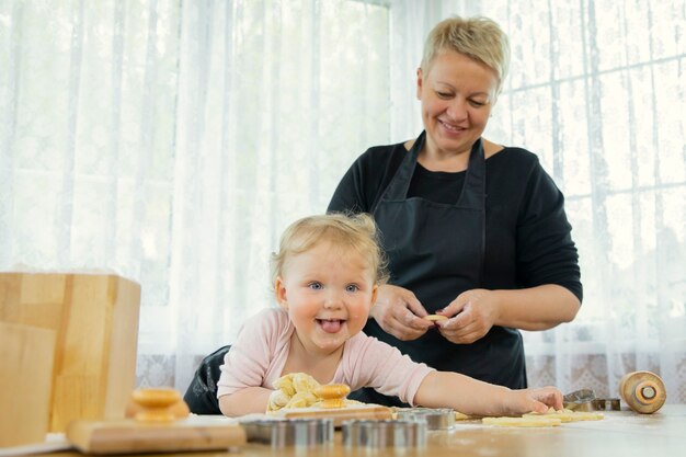 Enkelin wurde mit Mehl schmutzig, während sie ihrer glücklichen Großmutter half, Kekse zu machen