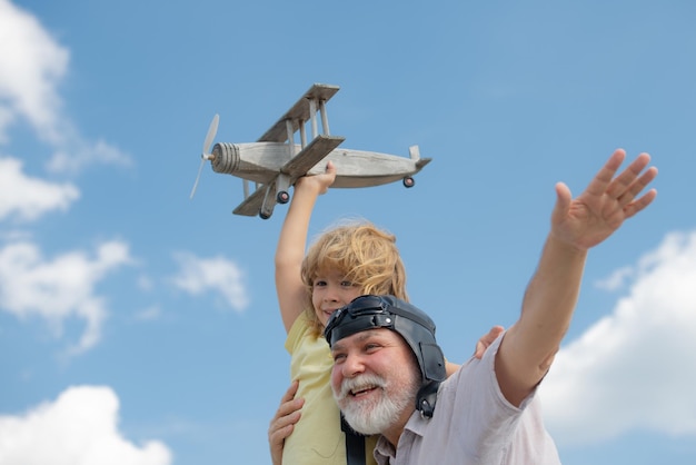 Enkelkind und Großvater amüsieren sich mit Spielzeugflugzeug am Himmel Kind träumt davon, glückliche Kinder zu fliegen