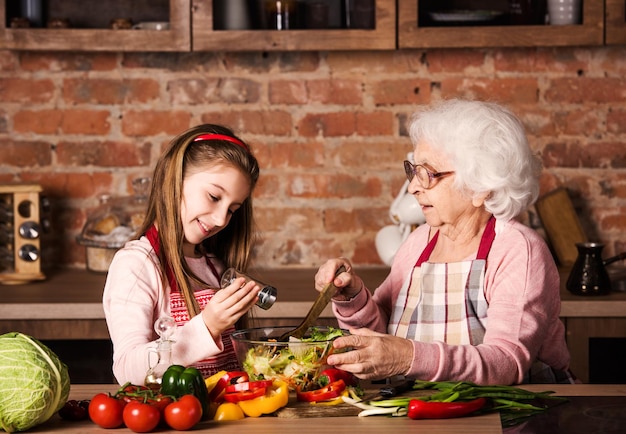 Enkelmädchen hilft ihrer Oma beim Kochen